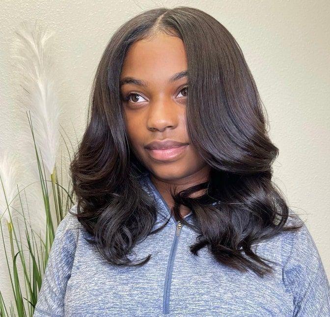 Shoulder-length sew-in with soft, bouncy curls and a middle part